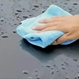 A hand holding a towel wipping a car