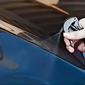 A hand using car nano and spraying a car