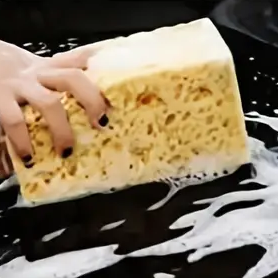 a hand holding a sponge and washing a car
